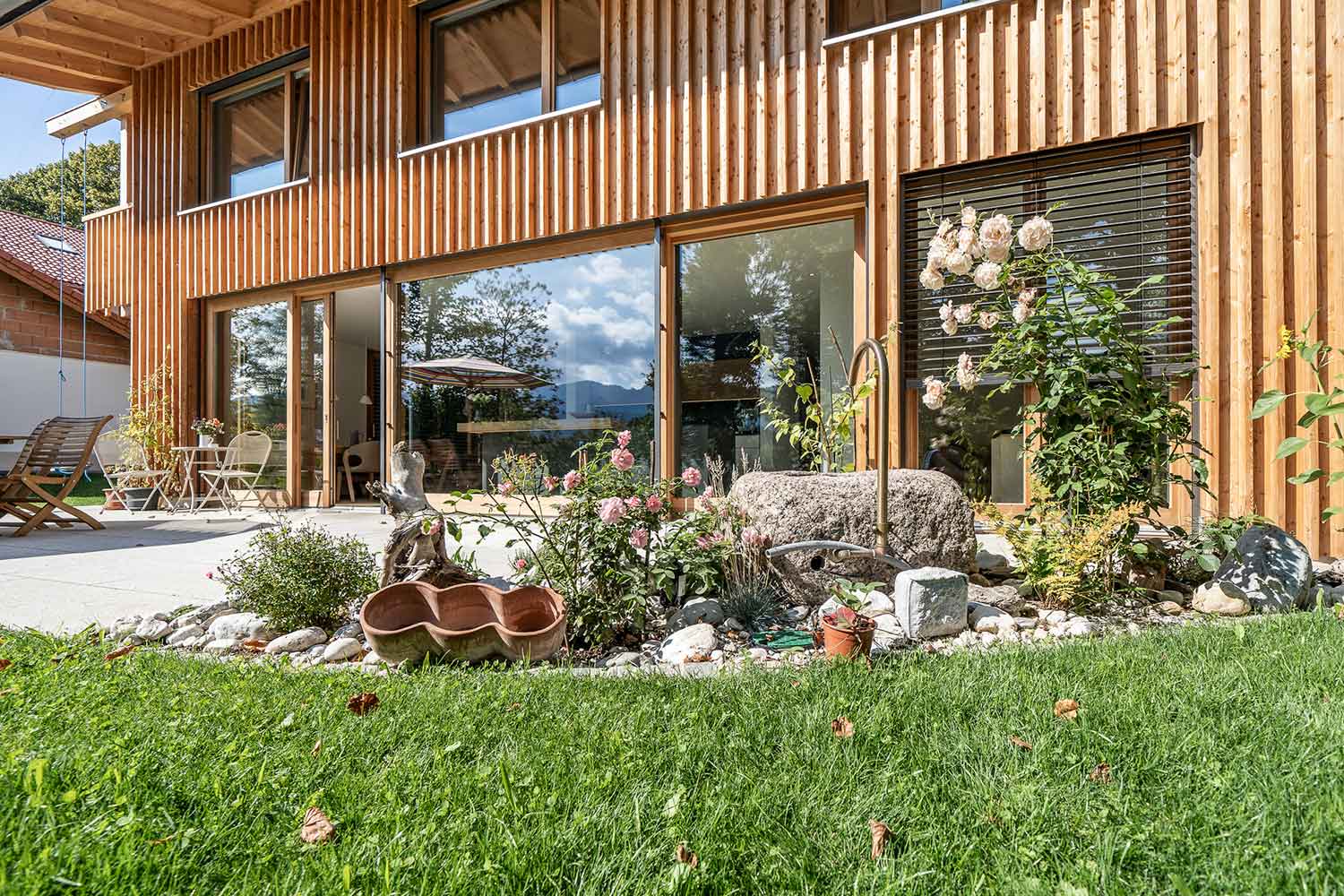 terrasse eines holzhauses mit gartenmoebel und bepflanzung