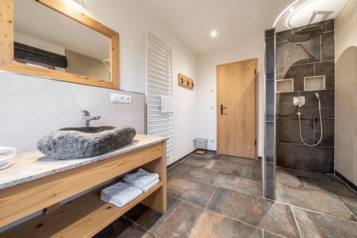 Badezimmer mit Waschbecken aus Stein und offener Dusche