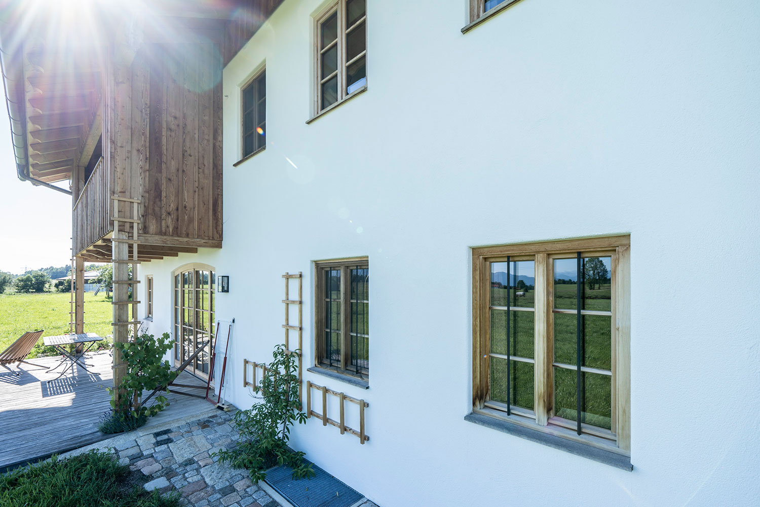 Fensterfront mit Zugang zum Wohnbereich von der Holzterrasse mit Loggia Balkon