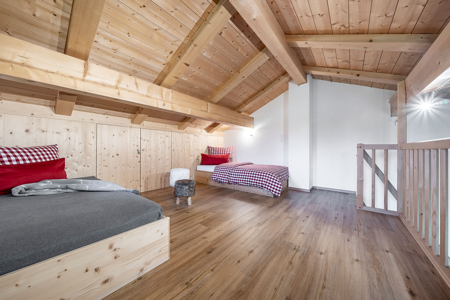 Galerieraum mit offenem Dachstuhl mit zwei betten aus holz